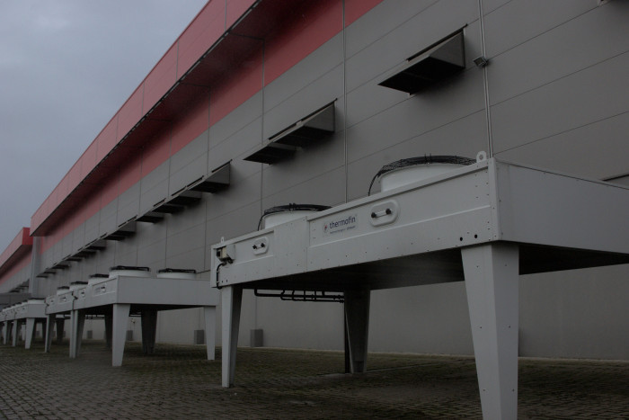 Eine Serverhalle von außen: Unten die Freikühler für besonders heiße Tage, durch den roten Vorsprung am Dach entweicht die warme Luft. (Bild: Johannes Hiltscher, Golem.de)