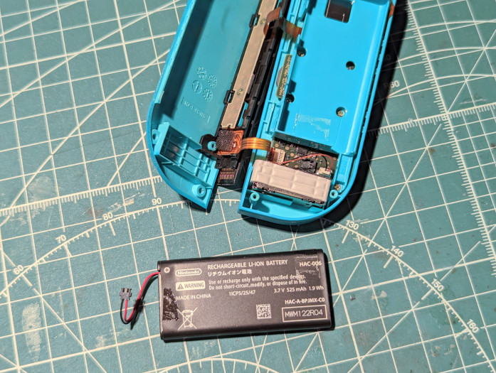 Der Akku ist nur mit zwei kleinen Klebepads fixiert und lässt sich leicht mit Hilfe des Kunststoffplektrums lösen. (Bild: Tobias Költzsch/Golem.de)