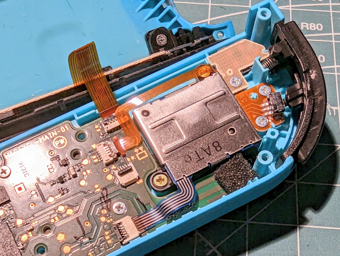 Anschließend entfernen wir auch das Flachbandkabel, das zu den Schultertasten führt - es liegt über einer Befestigungsschraube des Joysticks. (Bild: Tobias Költzsch/Golem.de)