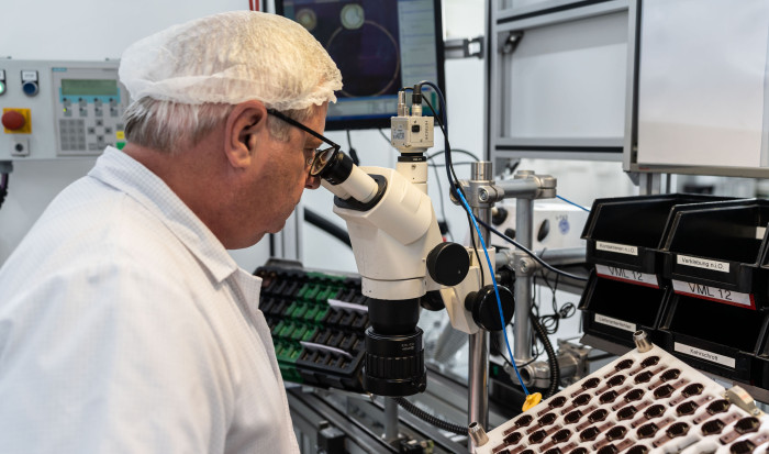 Zur Kontrolle einzelner Bauteile im Ultraschallsensor benötigt der Mitarbeiter ein Mikroskop. (Bild: Valeo)