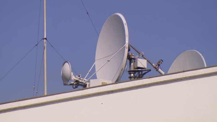 Diese Sendeantenne mit einem Durchmesser von rund 2 m sendet im Ku-Band, sie verfügt über einen Stellmotor, ist also drehbar. Daneben steht eine sendetaugliche Vertikalantenne für Kurzwelle. Beide sind vom Straßenniveau nur von einem ganz bestimmten Punkt aus sichtbar. (Bild: CC 3.0 Nomen Nescio)